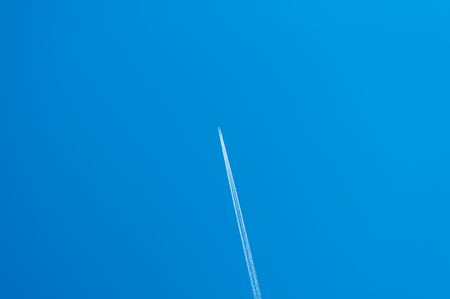white streaks of a plane in the blue skyの写真素材