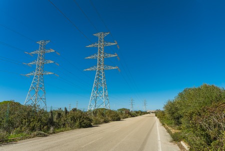country road near elettric pylons in a sunny morningの写真素材