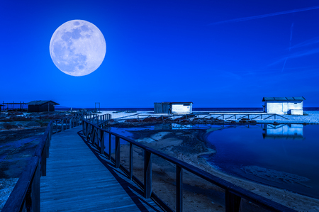 White cottage on the beach at night under the super moonの写真素材