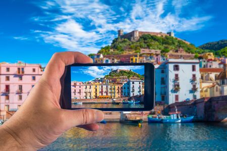 Hand taking picture with a smartphone in the village of Bosa, in Sardinia, in summerの写真素材