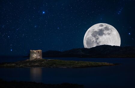 Night seascape in Sardinia with tower on the coast in La Pelosa Beach, in Stintino, with starry sky and super moonの写真素材