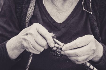 closeup on old lady hands to knitting in a terraceの写真素材