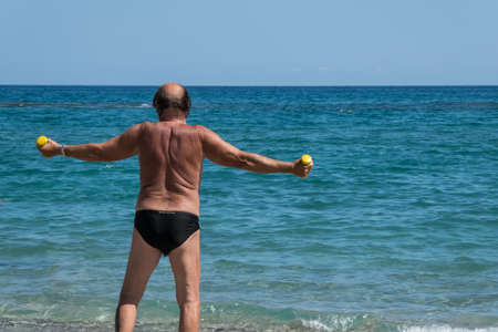 people on the beach in summer with old white man working out