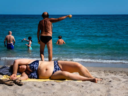 people on the beach in summer with old white man working outの写真素材