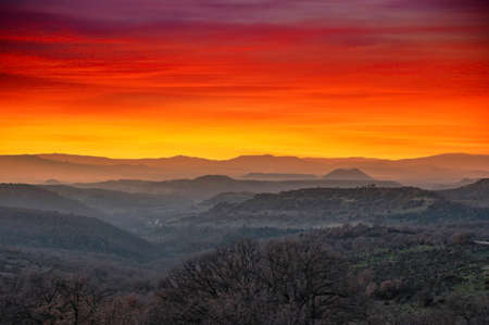 Landscape of mountains at sunset with dramatic red and orange skyの写真素材