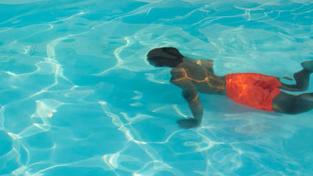 Child having fun in the pool. Joyful kids fun in the transparent blue water. Additional activities...