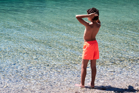 A young boy on the beach looking out to sea.の写真素材