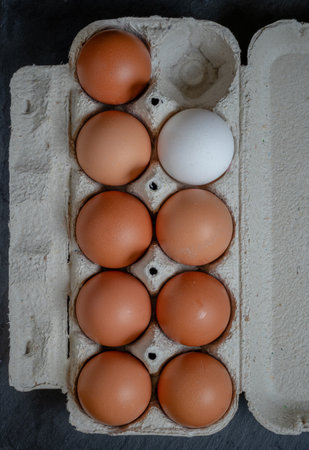 Fresh chicken eggs in a paper tray on the table, selective focus