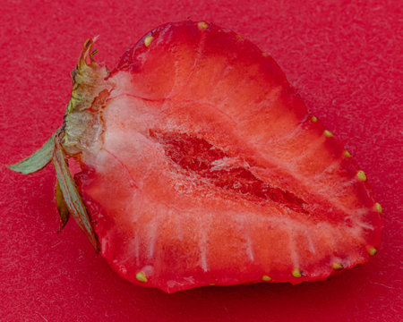Cut ripe strawberry on red background macro shotの写真素材
