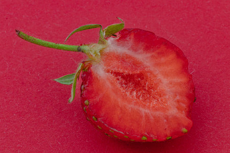 Cut ripe strawberry on red background macro shotの写真素材