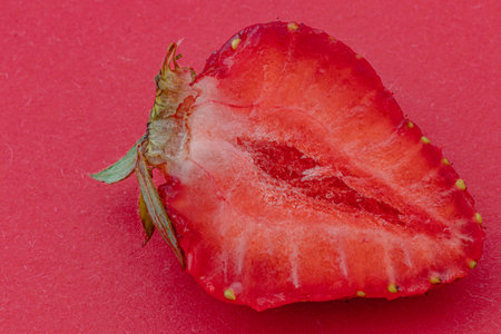 Cut ripe strawberry on red background macro shotの写真素材