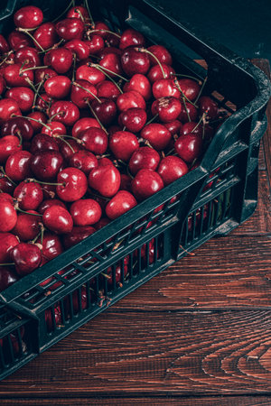 ripe cherries in a plastic box on the table top viewの写真素材