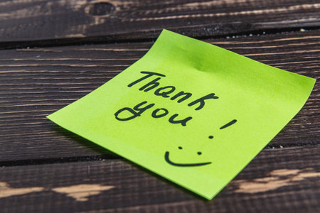 The word thank you for the light on a green leaf on a wooden background