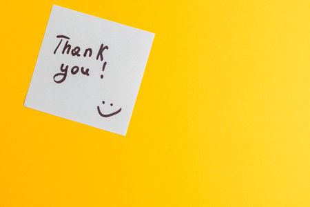 The word thank you on a white piece of paper on a yellow backgroundの写真素材
