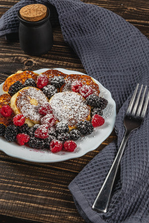 Cottage cheese pancakes with fresh raspberries, blackberries and powdered sugarの写真素材