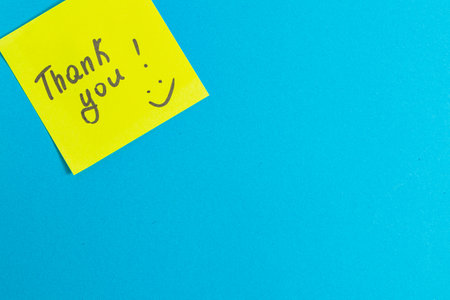 A yellow thank you note on a blue backgroundの写真素材