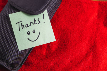 A soft black box on a red background with a turquoise thank you labelの写真素材