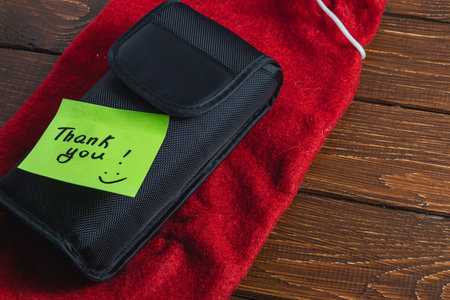 A soft black box on a red christmas bag with a green thank you label