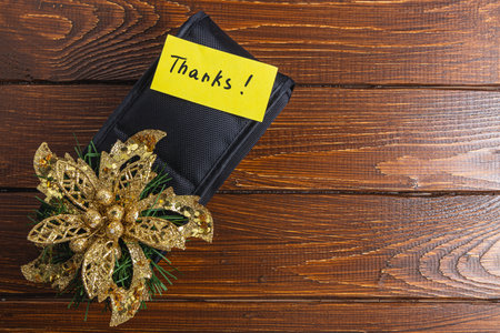 Long dark box on table with yellow thank you label and gold flower decorationの写真素材