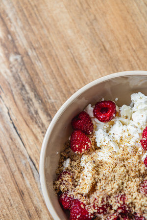 cottage cheese in a bowl with fresh raspberries and ground nuts, top viewの写真素材