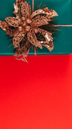 A green gift box with a golden flower on a red backgroundの写真素材