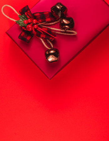 A red gift box with a bow and bells on a red background