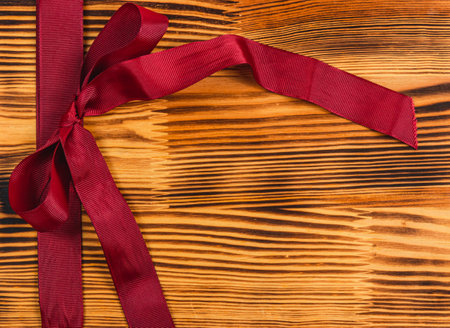 Dark red ribbon and bow on a beautiful wooden background Christmas conceptの写真素材