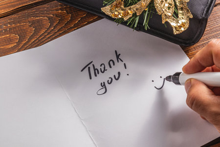 A person draws a smiley face on a piece of paper for the words of thanksの写真素材