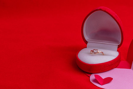 ring box with diamonds on a hand-cut paper heart on a red backgroundの写真素材