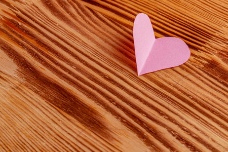 Pink heart cut out of paper on a wooden light backgroundの写真素材