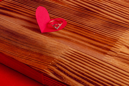 Wedding ring on a paper heart on a wooden boardの写真素材