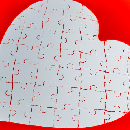Love concept. Heart puzzle print on white cardboard on red backgroundの写真素材