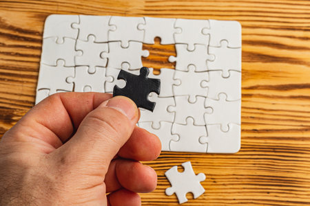 Hands holding black and white puzzle, concept of difficult option choice