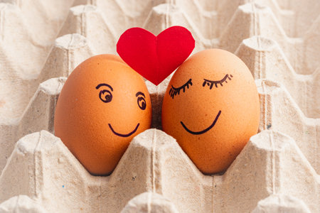 Painted eggs in a tray with a paper heart above them, love conceptの写真素材
