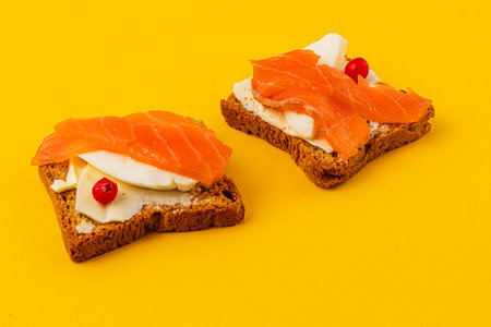 Salmon pieces on fresh toast spread with butter and a slice of mozzarellaの写真素材