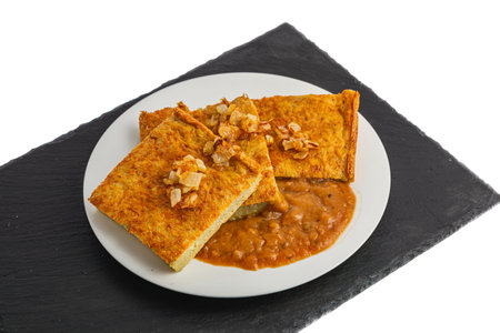 Oven-baked potato pancakes with mushroom sauce and onions on a stone board
