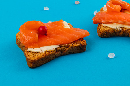 Fresh delicious croutons with salmon on a blue background, sprinkled with saltの写真素材