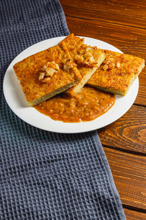 Baked potato pancakes with mushroom sauce on a gray towel and wooden table