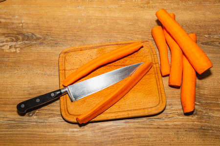 Carrots cut into pieces on a kitchen board, next to a knifeの写真素材