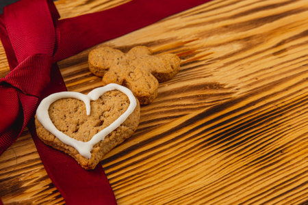Gingerbread cookies with heart shape and ribbon on wooden tableの写真素材