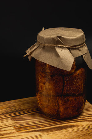 A jar filled with boiled and salted lard sits on a wooden table, wrapped with paper for preservation. The lard is complemented by pickled beans, showcasing homemade food preparations.の写真素材