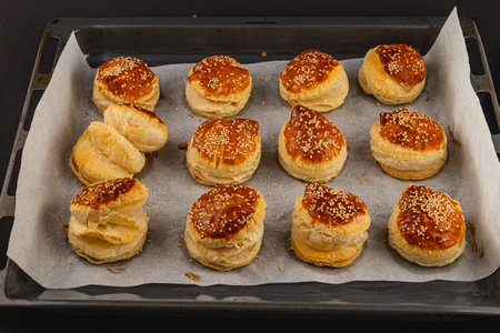 Freshly baked pastries sit on a tray, their golden crusts glistening in the light. Each treat is inviting a delightful taste experience.の写真素材