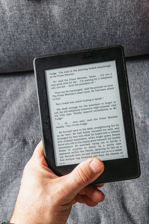 Holding an e book in hand while comfortably seated, immersed in a captivating story during a...
