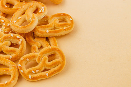Delicious crispy pretzels are casually scattered on a light background, showcasing their...