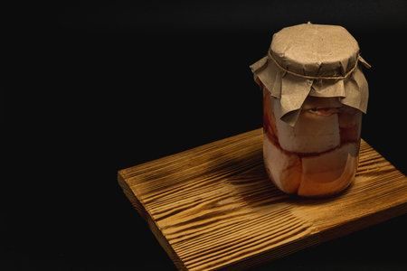A jar of homemade canned food sits on a wooden surface.の写真素材