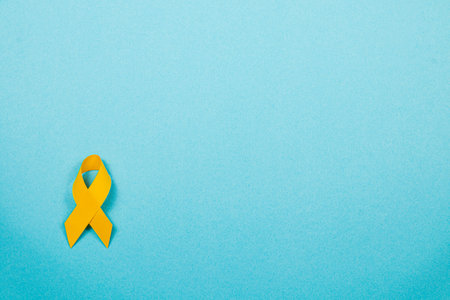 A yellow ribbon rests on a light blue background, representing awareness and solidarity in the...