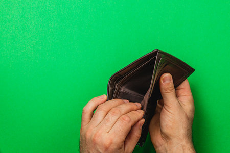 A businessman opens his empty leather wallet, reflecting feelings of despair and loss. He searches for cash amidst a personal finance crisis, feeling the weight of recession.の写真素材