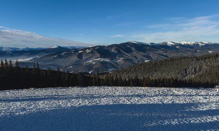 Scenic view of snow-covered mountains under a bright blue sky in Polyanytsia, Ukraine. This winter landscape captures the serene beauty of nature in January 2025.の写真素材