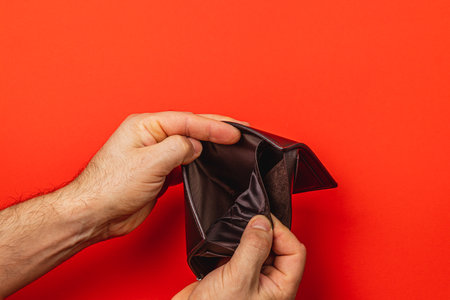 A businessman examines his empty wallet, reflecting on financial challenges and the impact of a recession on savings and expenses while searching for solutions to his crisis.の写真素材