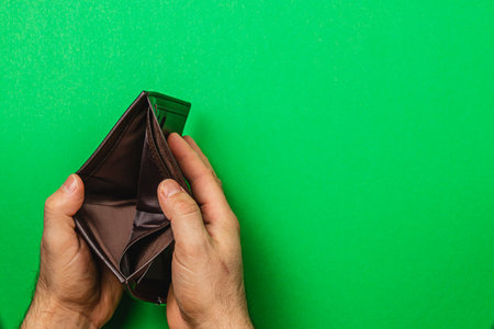 A person holds an empty wallet, conveying feelings of despair and loss during a financial crisis. Their hands reveal the reality of budgeting difficulties and economic challenges.の写真素材